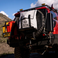 Rear view of off-road SUV with mounted Ötzi gear bag and spare tire on a mountain trail