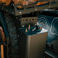 Close-up of a mounted fuel canister and gear tools on an off-road vehicle.