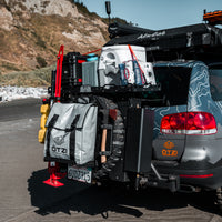 SUV equipped with overlanding gear including water containers, storage bags, and recovery tools