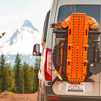 Orange recovery board and firewood mounted on the back of an off-road van with mountain view